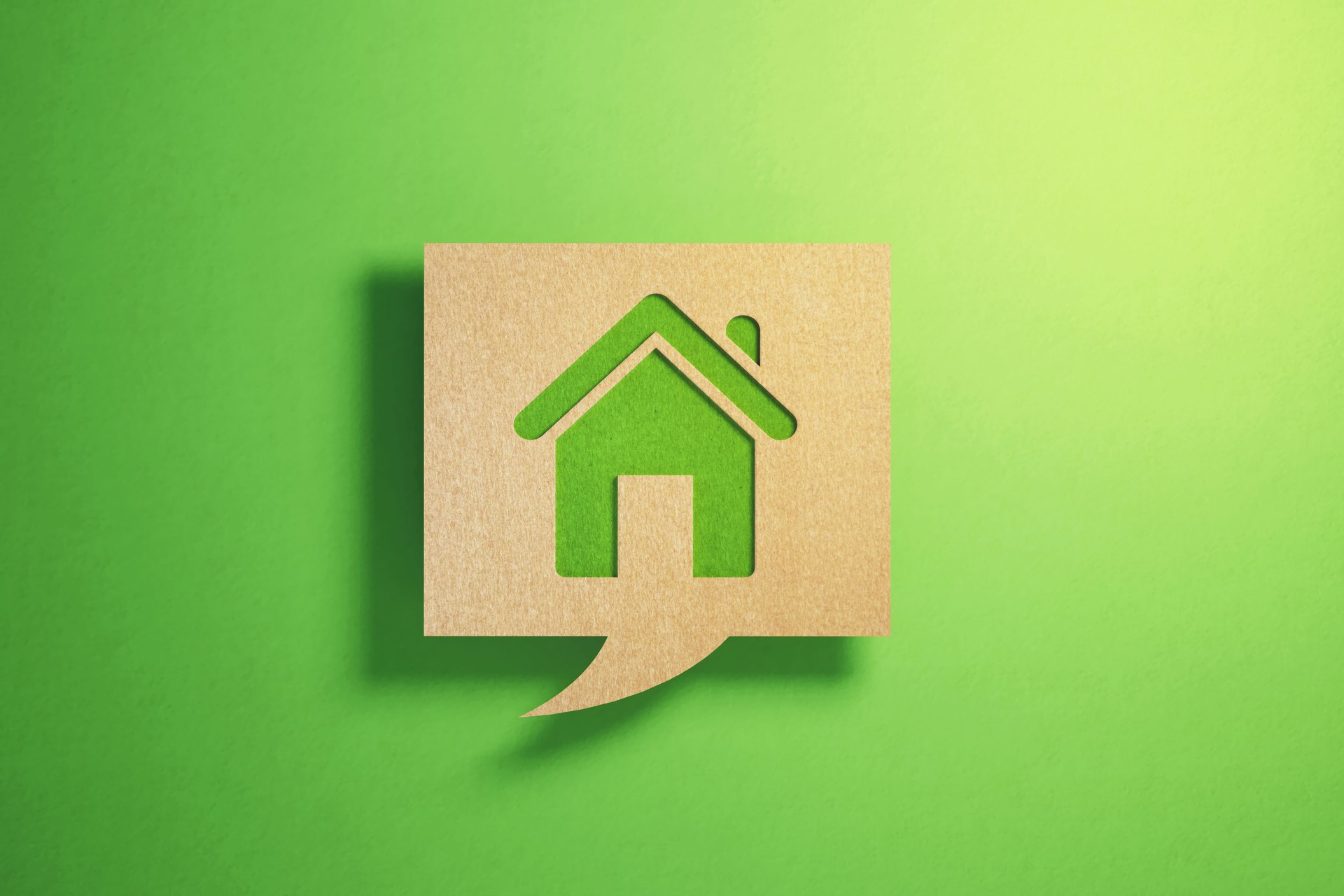 Sustainability Concept - House Symbol Imprinted Chat Bubble Made of Recycled Paper Sitting On Green Background